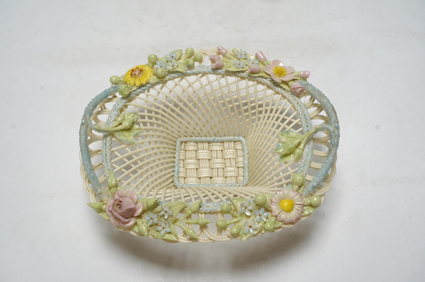 Three 20th century Belleek items with applied floral decorations; a jug, 15cm high, and two basket work dishes, largest 20cm wide. Condition - good